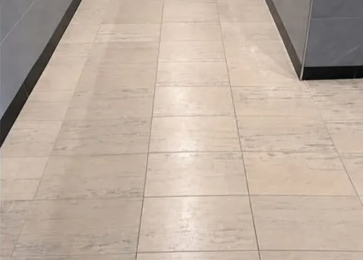 Corridor tile floor before restoration, dull and uneven in finish